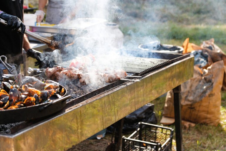 Defocus man cooking bbq meat at festival outdoor. Seafood paella. Chef grilling sausages in park outside. Concept of summer party with families and friends. Food festival. Out of focus.